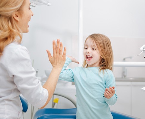 a child and her dentist high fiving