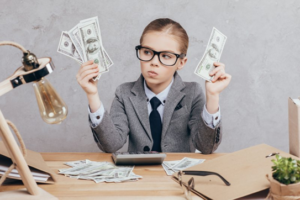 Child in business suite holding up wads of cash wondering what to do with them